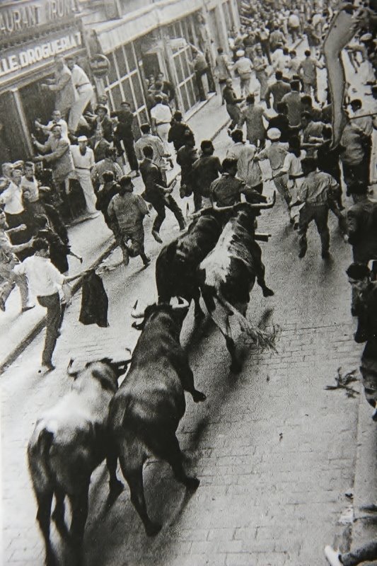 Matt Carney running in the centre of the street, on the horns of the bulls, in 1960